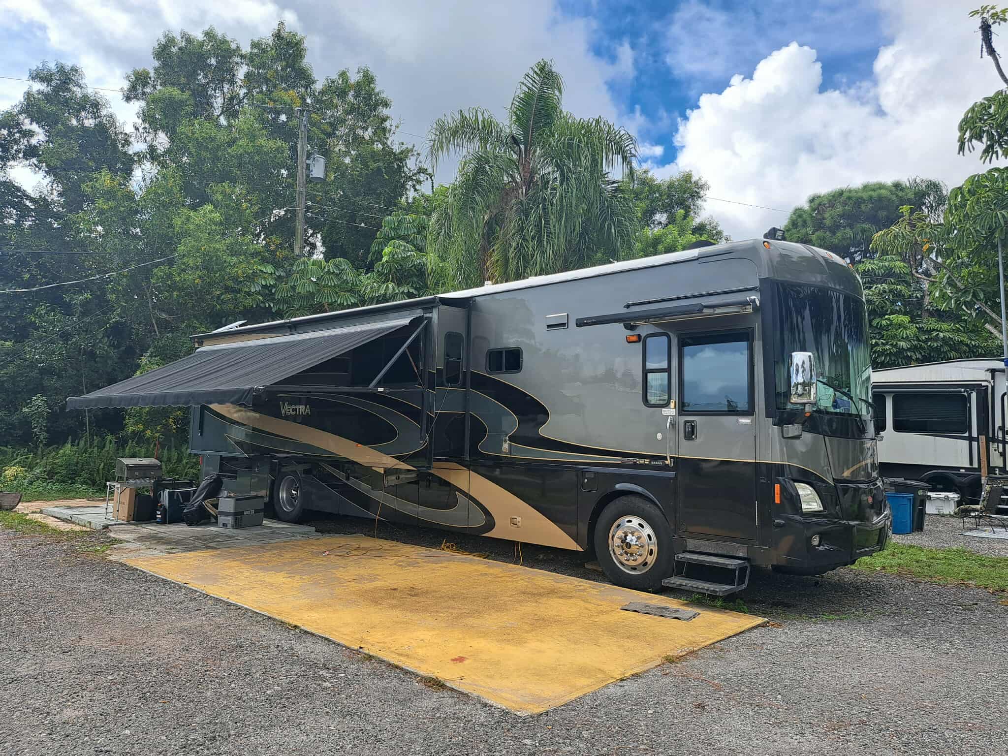 Luxury RV with awning on concrete pad at Twin Rivers